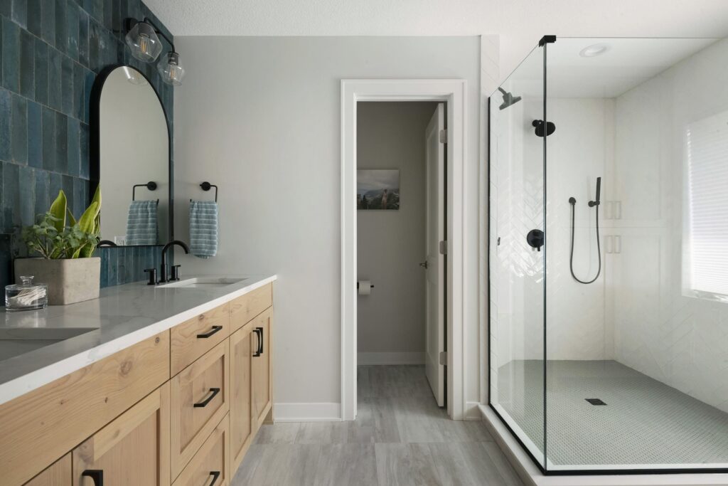 Contemporary bathroom with glass walk-in shower, natural wood vanity, and teal tile accent wall