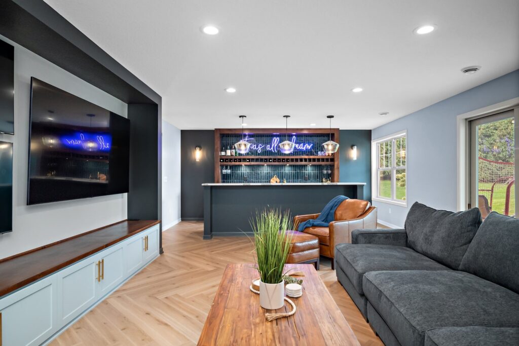 Stylish basement bar with dark cabinetry, pendant lighting, and neon sign reading “It was all a dream” 
