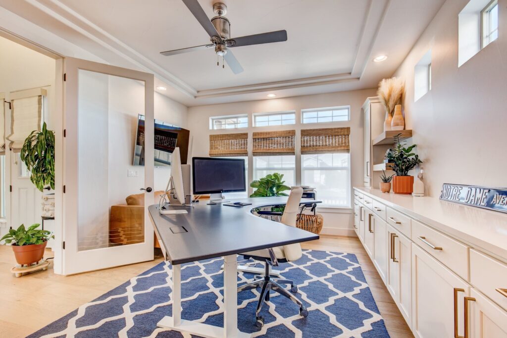 Home office with dual monitors, glass door entry, and built-in cabinetry