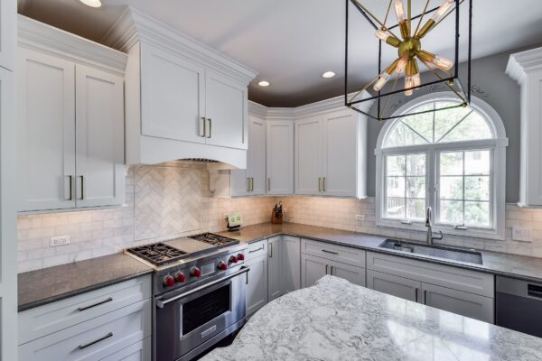 White kitchen with arched window, quartz counters, and gold hardware