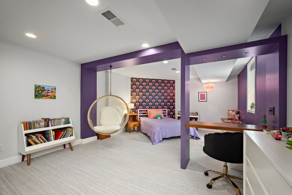 Colorful kids’ bedroom with purple built-in framing, swing chair, and patterned feature wall